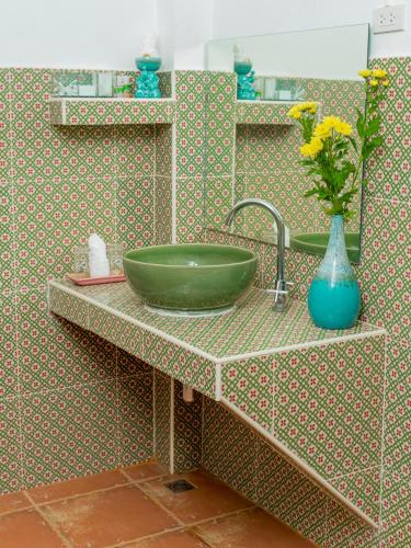 a bathroom with a green sink and a vase with flowers at Baan innto resort in Fang