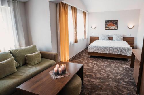 a hotel room with a bed and a couch and a table at Хотел Сидни in Banya