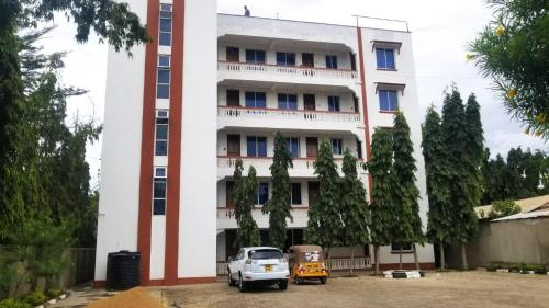 a white building with a car parked in front of it at Inviting 1-Bed Cozy Apartment in Mombasa in Mombasa