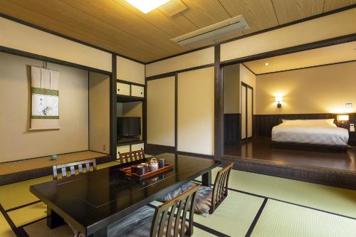 a room with a bed and a table and chairs at Yufuin Yufusaryo in Yufuin