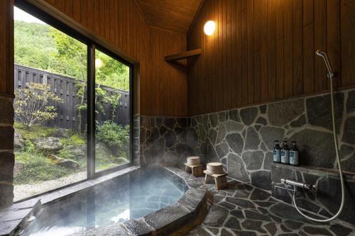 a large bathroom with a tub with a window at Yufuin Yufusaryo in Yufu