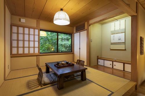 a room with a table and chairs and a window at Yufuin Yufusaryo in Yufuin
