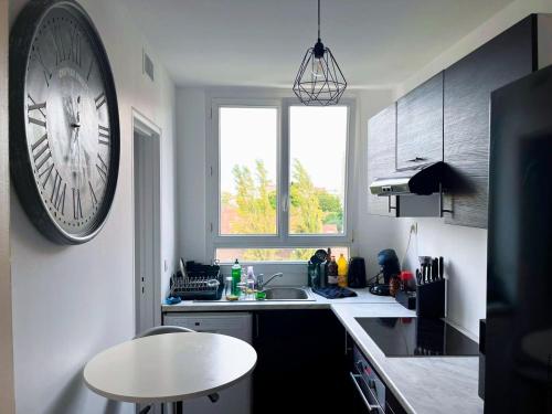 a kitchen with a clock on the wall and a sink at À 5 min de Paris , appartement calme,au pied du métro et très bien équipé in Maisons-Alfort