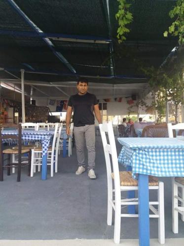 a man standing in front of tables and chairs at Kazonis Studios in Kalymnos