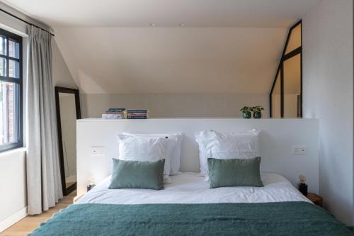 una camera da letto con un letto bianco con cuscini verdi e bianchi di De Sjieper a Lanaken