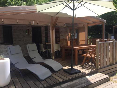 una terrazza in legno con tavolo, sedie e ombrellone di Sportcamping & Glamping Resort Rio Vantone a Crone