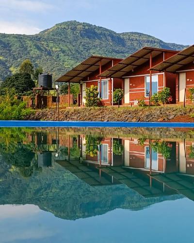 a house with a reflection in the water at Mysticstays Resort in Wai