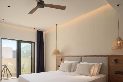 a bedroom with a white bed with a ceiling fan at Fodele Beach Water Park Resort in Fodele