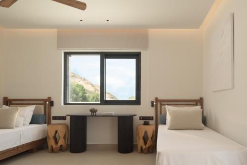 two beds in a room with a table and a window at Fodele Beach Water Park Resort in Fodele