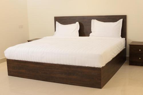 ein großes Bett mit weißer Bettwäsche und Kissen in der Unterkunft Durat Alnakheel Serviced Apartments in Unaizah