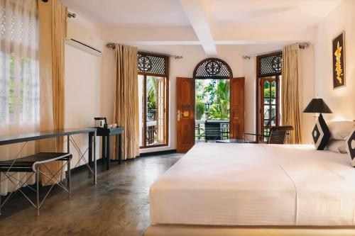Un dormitorio con una gran cama blanca y un escritorio. en AMAL VILLA, en Bentota