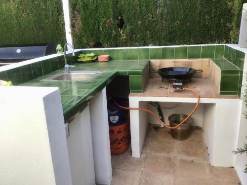 eine Außenküche mit einer Spüle und einem Grill in der Unterkunft Casa de 2 dormitorios con piscina, 2 terrazas privadas, WIFI, BBQ in Denia