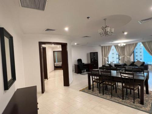 a dining room and living room with a table and chairs at Hotel Leaders Plaza Mahboula in Kuwait