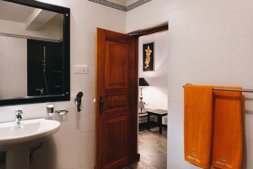 Un baño con lavabo y puerta de madera. en AMAL VILLA, en Bentota