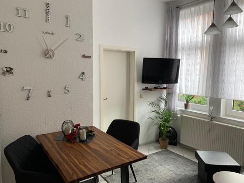 a living room with a table and a clock on the wall at Fewo-Liza in Wernigerode