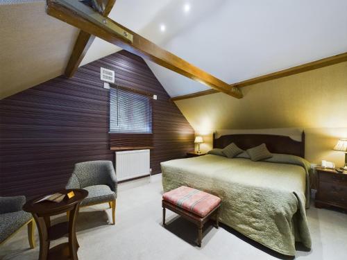 a bedroom with a large bed and two chairs at Beech House Hotel in Reading