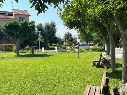 a park with two benches and trees and a car at Hotel Park in Rossano