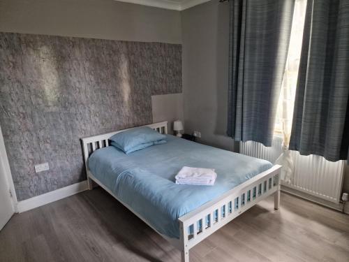 um quarto com uma cama com lençóis azuis e uma janela em Tower Gardens Residence em Londres
