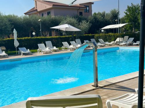 a fountain in a swimming pool with chairs and umbrellas at Hotel Park in Rossano