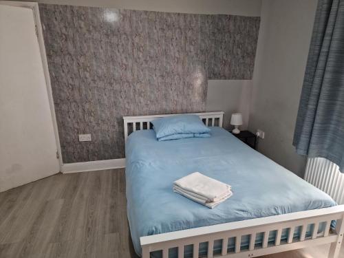 a bedroom with a bed with blue sheets and towels on it at Tower Gardens Residence in London