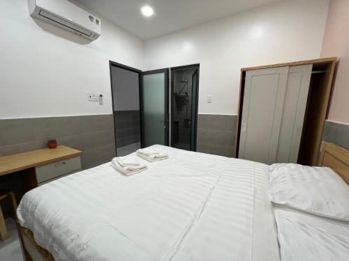een slaapkamer met een wit bed en 2 handdoeken bij MY Homestay in Cà Mau