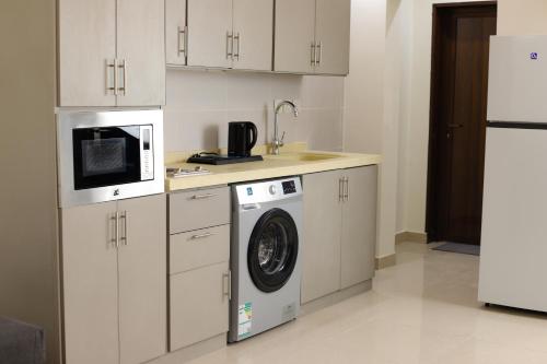 Durat Alnakheel Serviced Apartments في عنيزة: مطبخ مع غسالة ملابس وميكرويف