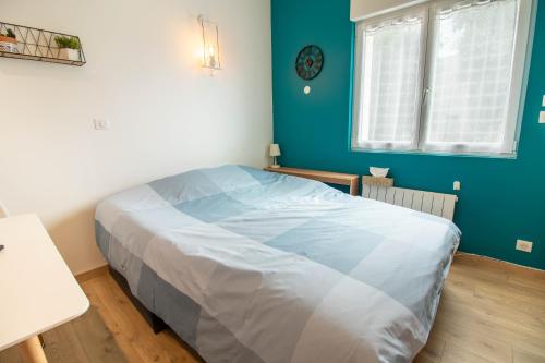 Bett in einem Zimmer mit blauer Wand in der Unterkunft Studio duplex, proche université in Montbéliard