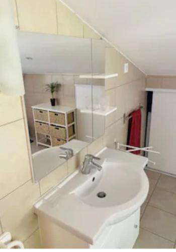 une salle de bain avec un lavabo blanc et un miroir dans l'établissement Dolce Notte, l'idéal pour des vacances à Bastia - Appartement avec vue panoramique et piscine sur les hauteurs, à Bastia