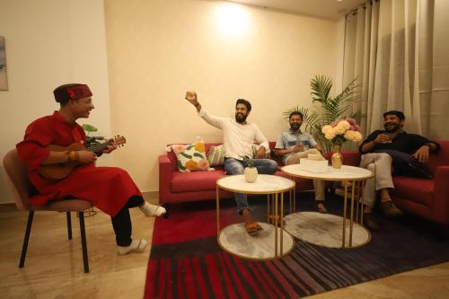 a group of men sitting in a living room playing music at Perfectstayz Value Homes Mussoorie 120 meters uphill in Mussoorie