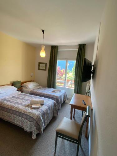 a hotel room with two beds and a table and a window at Garden Hotel Bellariva in Molveno