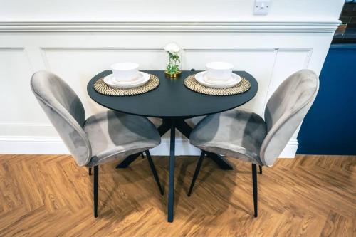 a black table with two chairs and two plates on it at The Former New Inn, air conditioning in Ashby de la Zouch