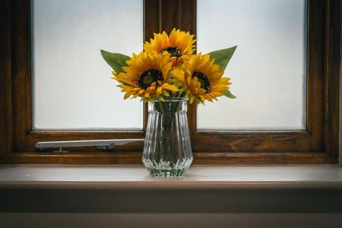 a vase filled with yellow flowers sitting on a window sill at The Former New Inn, air conditioning in Ashby de la Zouch