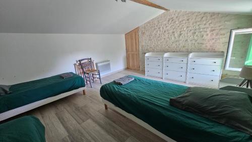 a bedroom with two beds and a chair in it at Le gîte de Malécot Gîte familial de 5 personnes in Coulon