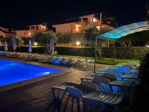 a pool with chairs and umbrellas at night at Hotel Park in Rossano