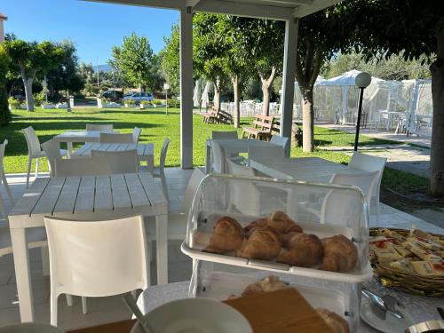 a table with white tables and white chairs and food at Hotel Park in Rossano