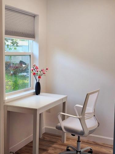 Spacious Bedroom with private workspace, ensuite bathroom - Room# 1 in SHARED house NO PET في أورلاندو: مكتب أبيض مع كرسي أبيض و مزهرية مع الزهور