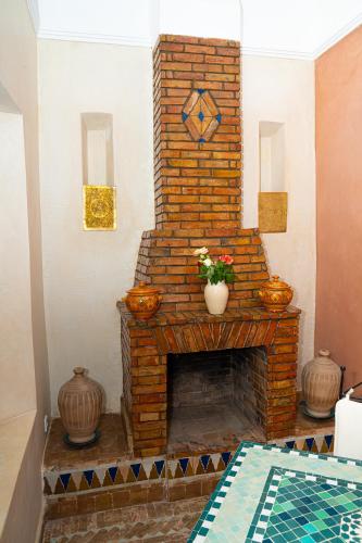 a brick fireplace in a living room with a table at Riad Dar Zaouia in Marrakech