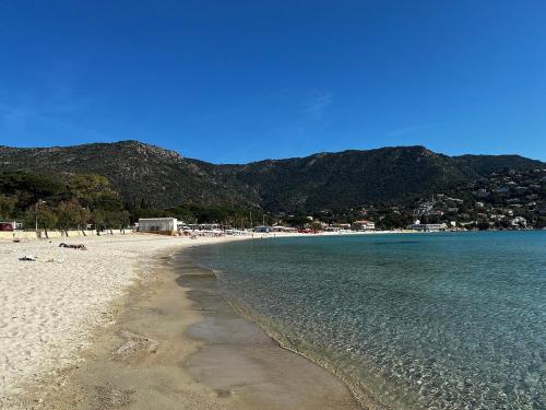 a beach with the ocean and mountains in the background at Le Lavandou 6 pers. + parking privé + terrasse (au calme) in Le Lavandou