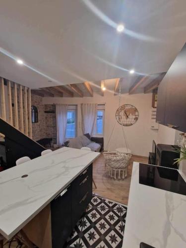 une cuisine avec des comptoirs blancs et un salon dans l'établissement Maison chaleureuse, centre bourg, à Casson