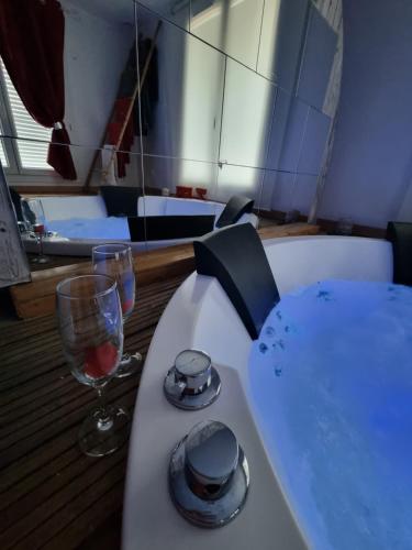 a table with a glass of wine next to a bath tub at Le Rêve de Lily in Les Vignères