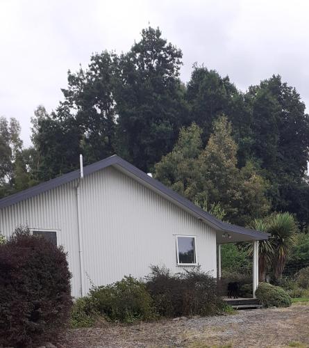 a white building with trees in the background at Tui Haven in Te Moana