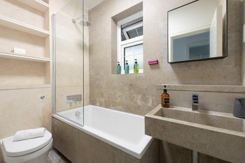 a bathroom with a tub and a toilet and a sink at 2 BR, Modern Urban Sanctuary 1CC in London