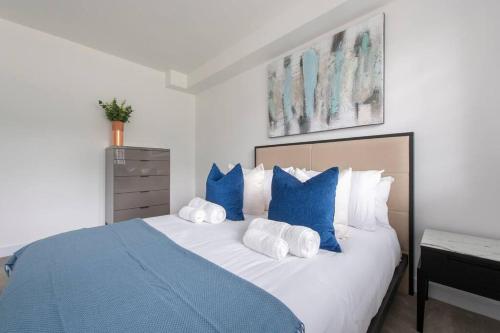 a bedroom with a large bed with blue and white pillows at 2 BR, Modern Urban Sanctuary 1CC in London