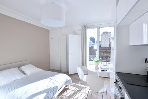 um quarto branco com uma cama, uma mesa e cadeiras em Studio 1 Pièce 20 m2 em Paris