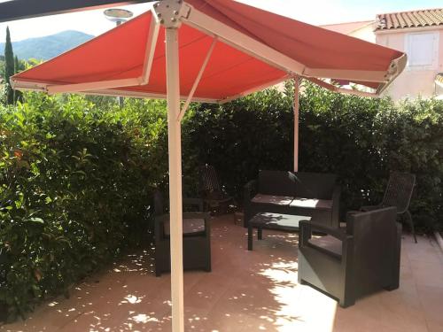 a red umbrella sitting on top of a patio at Belle Petite Villa climatisée dans résidence calme in Sorède