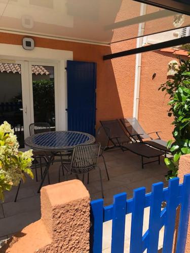 une terrasse avec une table, des chaises et une clôture bleue dans l'établissement Belle Petite Villa climatisée dans résidence calme, à Sorède