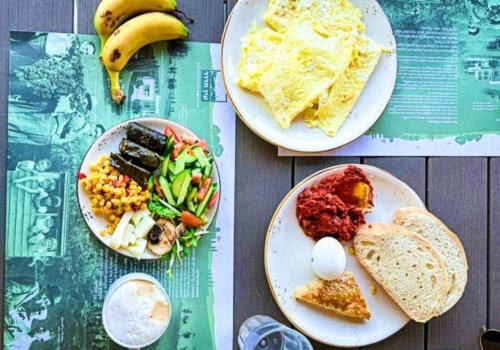 zwei Teller Essen auf einem Tisch mit Frühstückszutaten in der Unterkunft Ein Harod Country Lodge in ‘En H̱arod