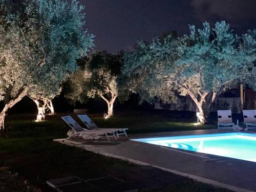 een zwembad met 2 ligstoelen en bomen in de nacht bij Relais Ruggiero in Le Castella