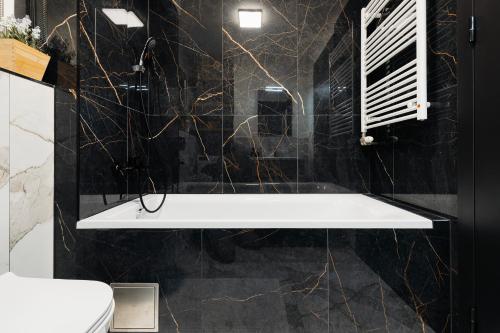 a bathroom with a white tub and black marble walls at Garden Apartment in Banská Bystrica