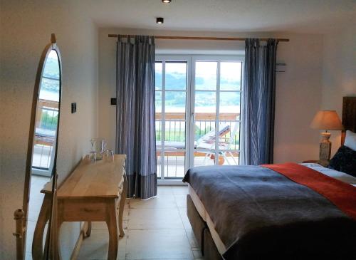 a bedroom with a bed and a desk and a window at Roiderhof Irrsee in Oberhofen am Irrsee